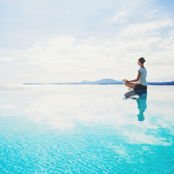 femme qui se sent bien en train de faire une séance de yoga au bord de l'eau.